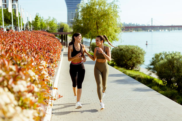 two women outside running and exercising